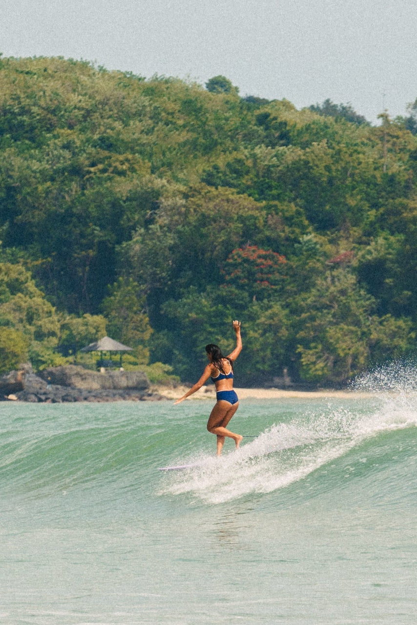 surfer girl cross stepping on a classic longboard by from earth, surfboards for sale in bali